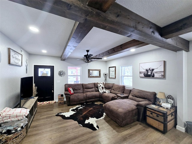 living room with beam ceiling, a textured ceiling, baseboards, and wood finished floors