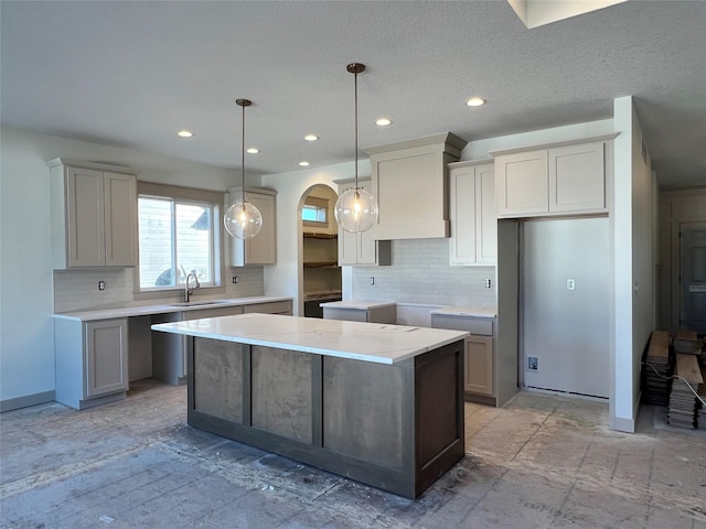 kitchen featuring hanging light fixtures, a kitchen island, sink, and gray cabinets