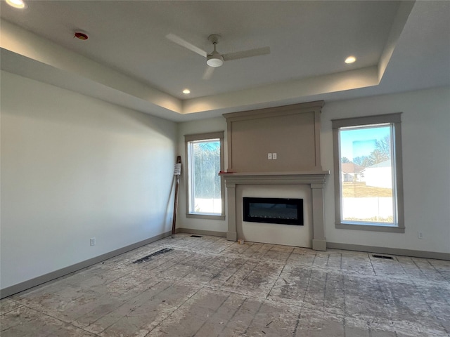 unfurnished living room with a tray ceiling and ceiling fan