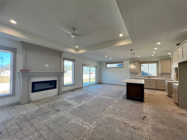 kitchen with hanging light fixtures, a tray ceiling, plenty of natural light, and a center island