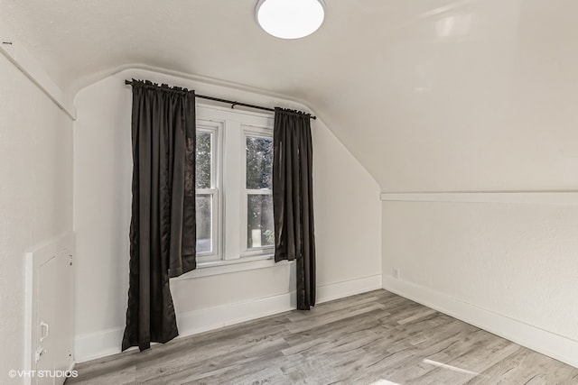 bonus room featuring light wood-type flooring and vaulted ceiling