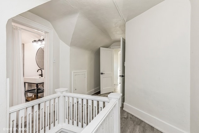 bedroom featuring a crib, light hardwood / wood-style floors, vaulted ceiling, and sink