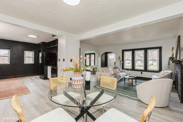 dining room with light wood-type flooring and a textured ceiling