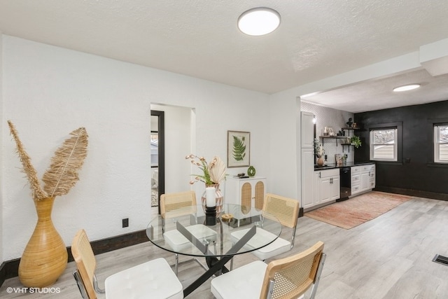 dining area featuring indoor bar, a textured ceiling, and light wood-type flooring