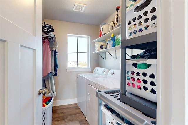 laundry room with a textured ceiling, light hardwood / wood-style floors, and washing machine and clothes dryer