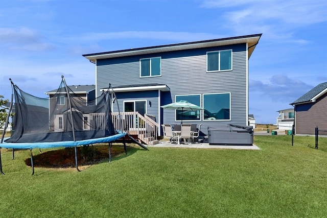 back of property featuring a trampoline, a lawn, and a patio area