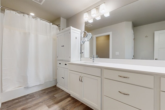 bathroom with shower / bathtub combination with curtain, hardwood / wood-style flooring, and vanity