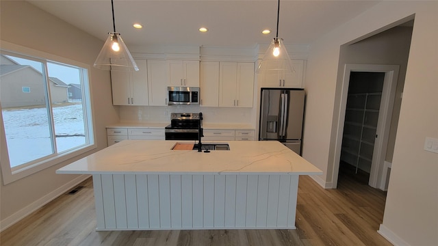 kitchen featuring an island with sink, pendant lighting, and appliances with stainless steel finishes