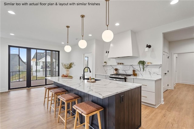 kitchen featuring white cabinetry, decorative light fixtures, and an island with sink