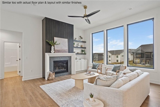 living room with light hardwood / wood-style floors, ceiling fan, and a large fireplace