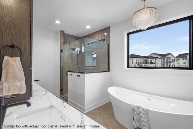 bathroom featuring tile patterned floors, an inviting chandelier, plus walk in shower, and vanity