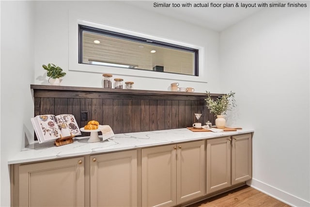 bar featuring light stone counters and light hardwood / wood-style flooring