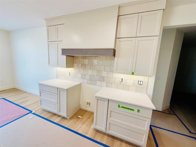 kitchen featuring light wood-type flooring, white cabinetry, and backsplash