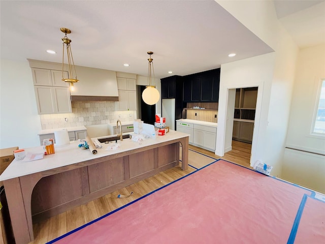 kitchen with sink, a center island with sink, decorative backsplash, and decorative light fixtures