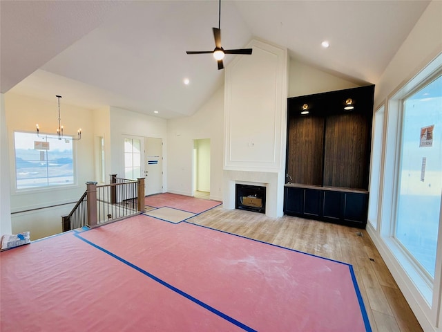 unfurnished living room featuring light wood-type flooring, high vaulted ceiling, and a notable chandelier