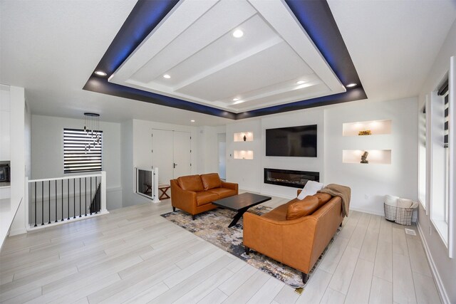 living room featuring a raised ceiling and light hardwood / wood-style floors