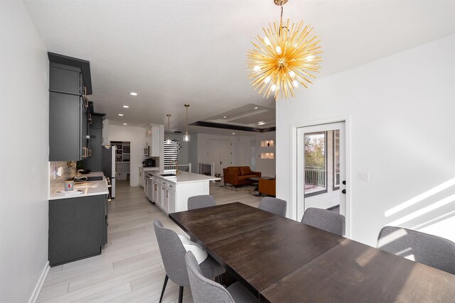 dining room featuring a raised ceiling, an inviting chandelier, and light hardwood / wood-style flooring