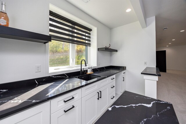 kitchen featuring dark stone counters, carpet floors, sink, and white cabinets