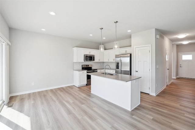 kitchen featuring white cabinets, sink, a center island with sink, appliances with stainless steel finishes, and light wood-type flooring