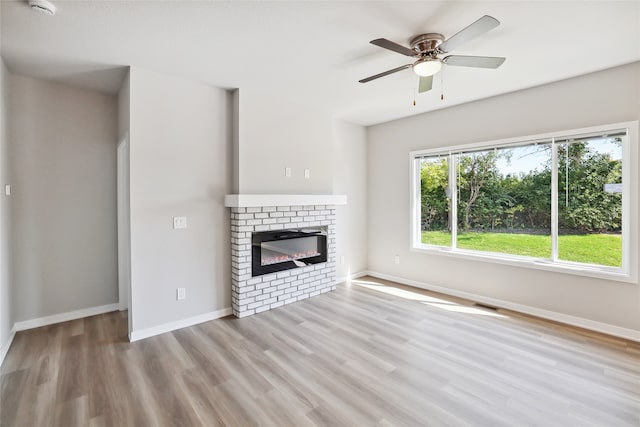 unfurnished living room with a brick fireplace, light hardwood / wood-style floors, and ceiling fan