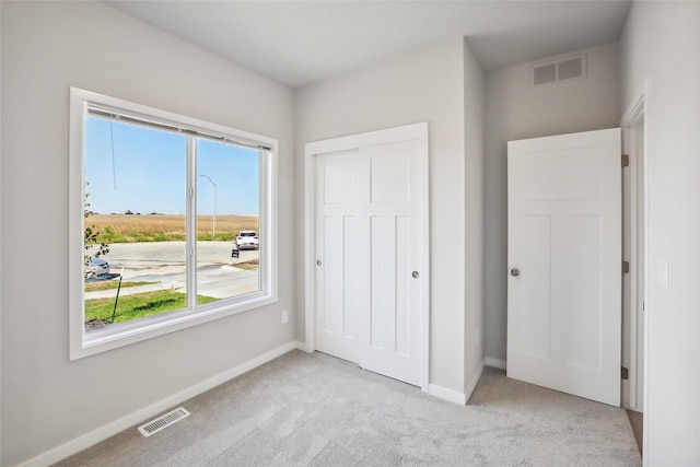 unfurnished bedroom featuring light colored carpet and a closet