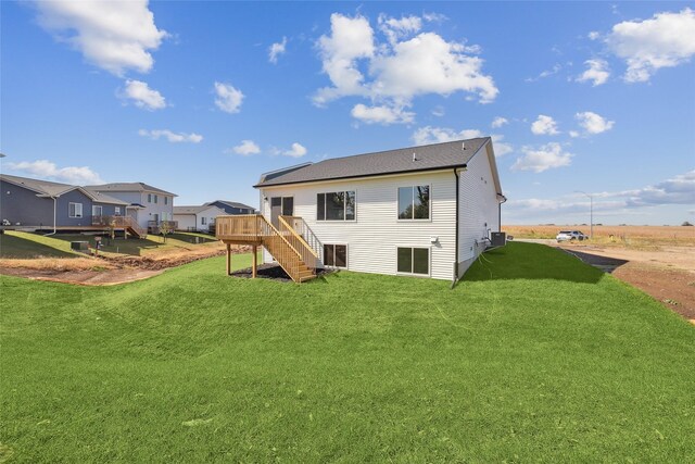 rear view of property with central AC unit, a yard, and a deck