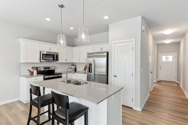 kitchen featuring sink, white cabinetry, backsplash, a kitchen island with sink, and stainless steel appliances