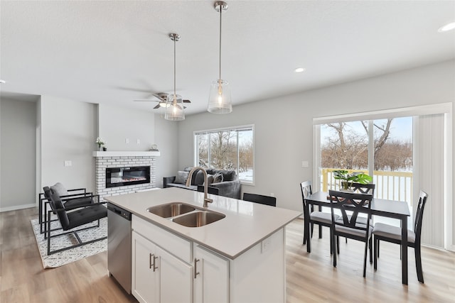 kitchen featuring sink, white cabinetry, a center island with sink, dishwasher, and light hardwood / wood-style floors