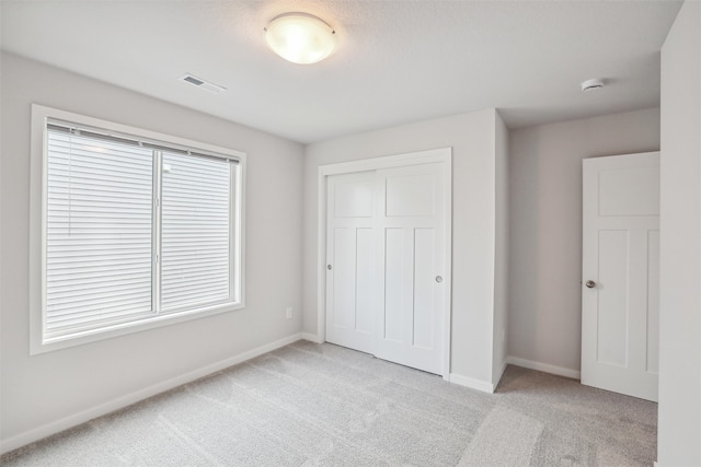 unfurnished bedroom with light carpet and a closet