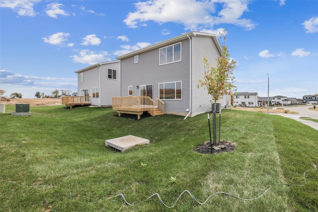 rear view of house with a yard, a deck, and cooling unit