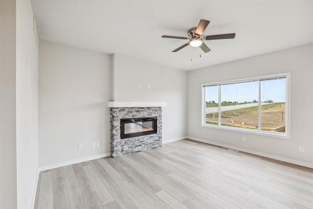 unfurnished living room featuring a fireplace, light wood-type flooring, and ceiling fan