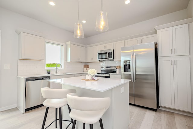 1703 Gordon Ct, Norwalk, IA 50211 - kitchen featuring appliances with stainless steel finishes, light wood-style flooring, a kitchen island, tasteful backsplash, and recessed lighting