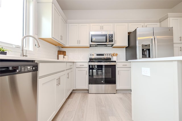 1703 Gordon Ct, Norwalk, IA 50211 - kitchen featuring appliances with stainless steel finishes, light countertops, decorative backsplash, and white cabinetry