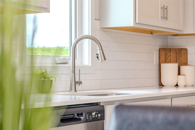 1703 Gordon Ct, Norwalk, IA 50211 - kitchen view of decorative backsplash, light countertops, white cabinetry, and stainless steel dishwasher