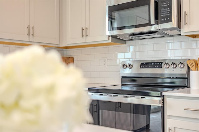 1703 Gordon Ct, Norwalk, IA 50211 - kitchen featuring stainless steel appliances, tasteful backsplash, light countertops, and white cabinetry