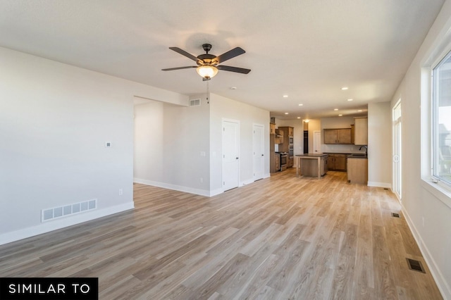 unfurnished living room with light hardwood / wood-style flooring, ceiling fan, and sink