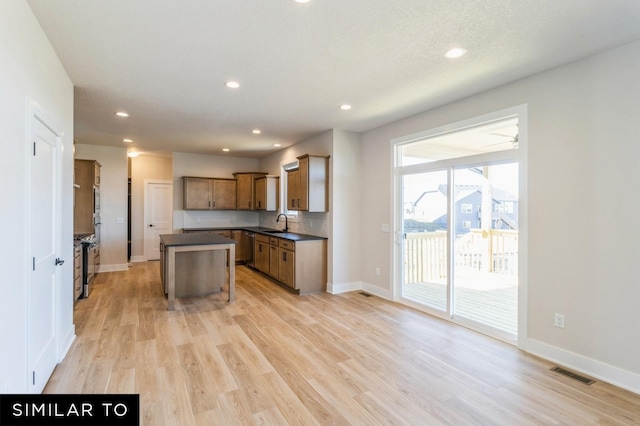 kitchen featuring a breakfast bar, dishwasher, sink, light hardwood / wood-style floors, and a kitchen island