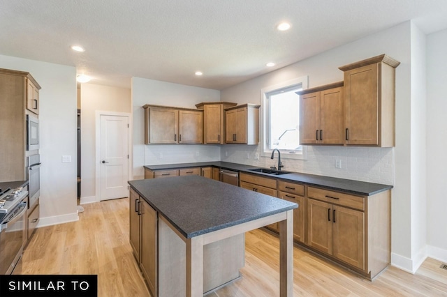 kitchen featuring sink, stainless steel appliances, light hardwood / wood-style flooring, backsplash, and a kitchen island