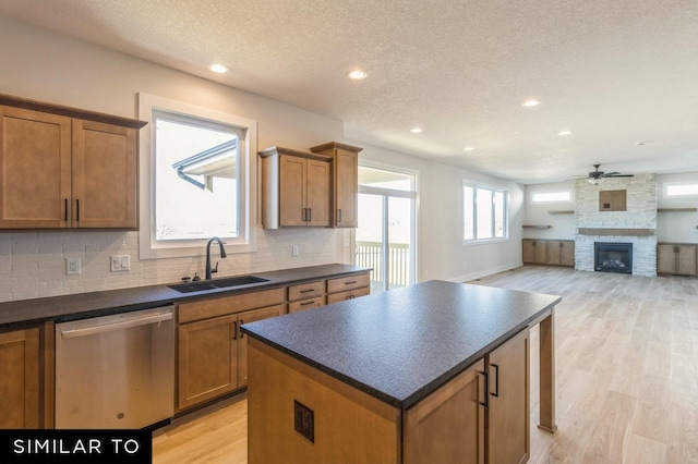 kitchen with ceiling fan, dishwasher, a center island, sink, and light wood-type flooring