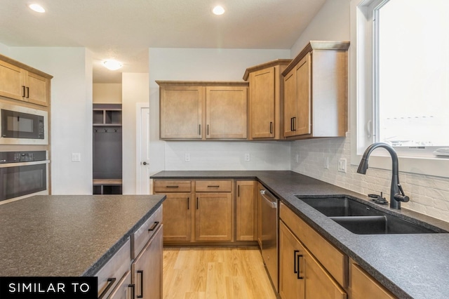 kitchen featuring appliances with stainless steel finishes, light wood-type flooring, tasteful backsplash, and sink