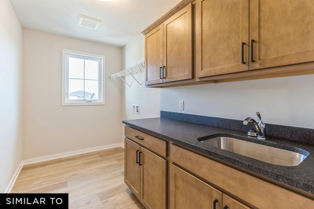 kitchen with sink, dark stone counters, and light hardwood / wood-style flooring