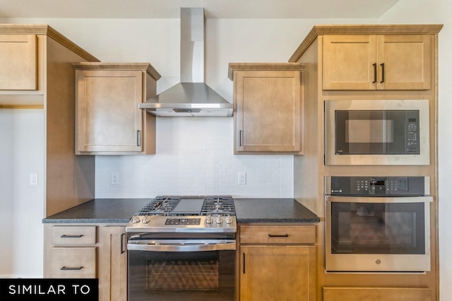 kitchen featuring decorative backsplash, stainless steel appliances, dark stone countertops, and wall chimney range hood