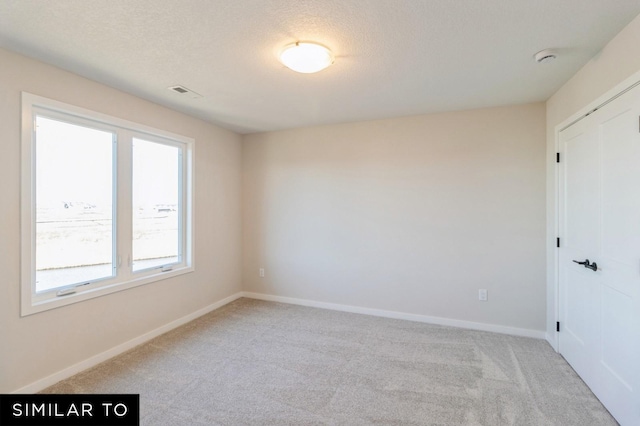 unfurnished room with light colored carpet and a textured ceiling