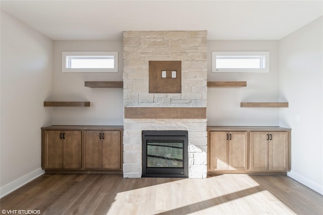 kitchen featuring a stone fireplace, dark wood-type flooring, and a wealth of natural light