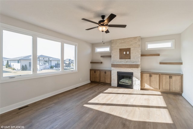 unfurnished living room featuring ceiling fan, a stone fireplace, and light hardwood / wood-style flooring