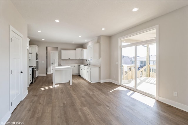 kitchen with stainless steel range, hardwood / wood-style flooring, white cabinets, and a kitchen island