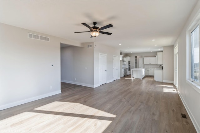 unfurnished living room with sink, hardwood / wood-style flooring, and ceiling fan