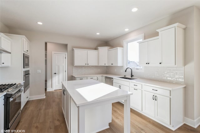 kitchen with appliances with stainless steel finishes, sink, a kitchen island, and white cabinets