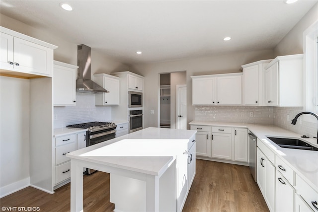 kitchen with wall chimney exhaust hood, sink, a kitchen island, stainless steel appliances, and white cabinets