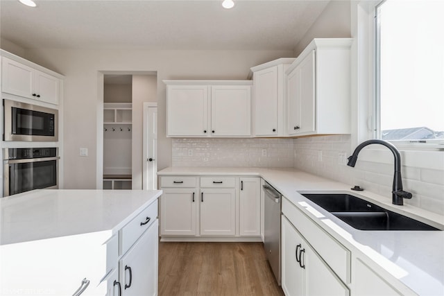 kitchen with tasteful backsplash, sink, stainless steel appliances, and white cabinets